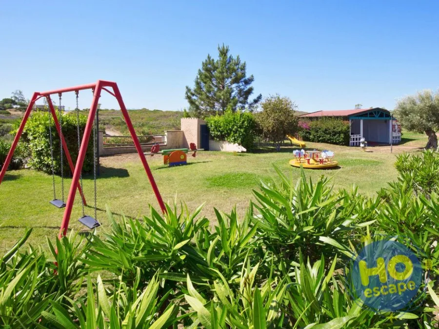 Area giochi per bambini con altalena, scivolo e giostrine nel parco verde