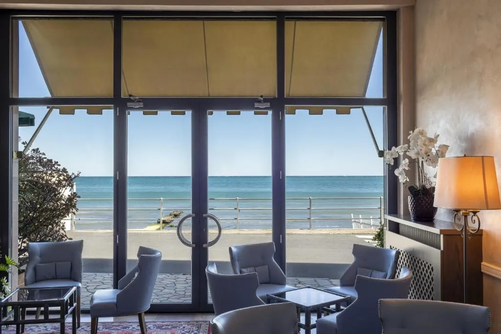 Area lounge con poltrone e vista sul mare attraverso le porte vetrate