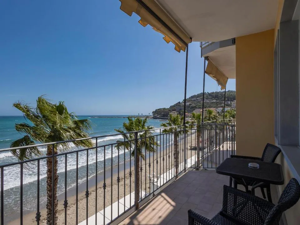 Balcone con sedie e vista sulla spiaggia, palme e mare azzurro