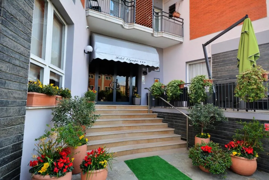 Ingresso dell'Hotel Olympic con scalinata, piante in vaso e fiori colorati