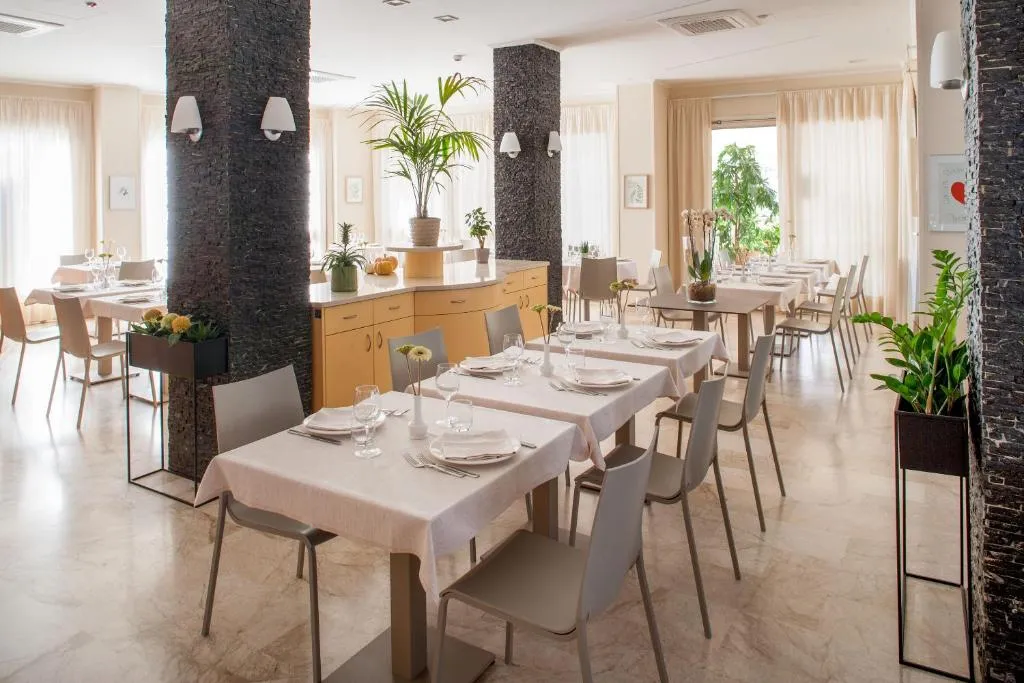 Sala ristorante elegante con tavoli apparecchiati, colonne in pietra e piante