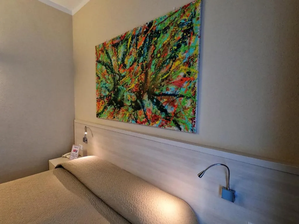 Dettaglio della testata del letto con quadro colorato astratto e luci di lettura