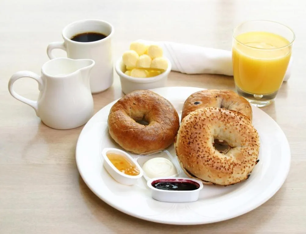 Colazione con bagel, caffè, latte e succo d'arancia