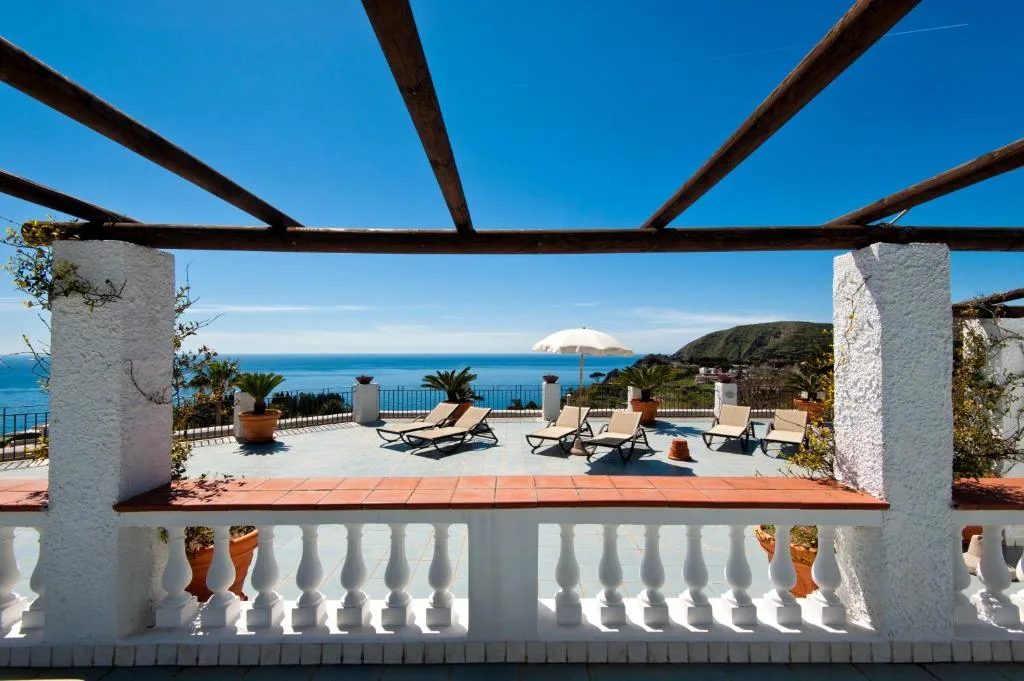Terrazza con balaustra bianca, lettini e ombrellone affacciata sul mare