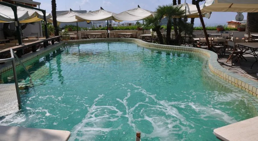 Piscina idromassaggio con acqua verde e ombrelloni bianchi