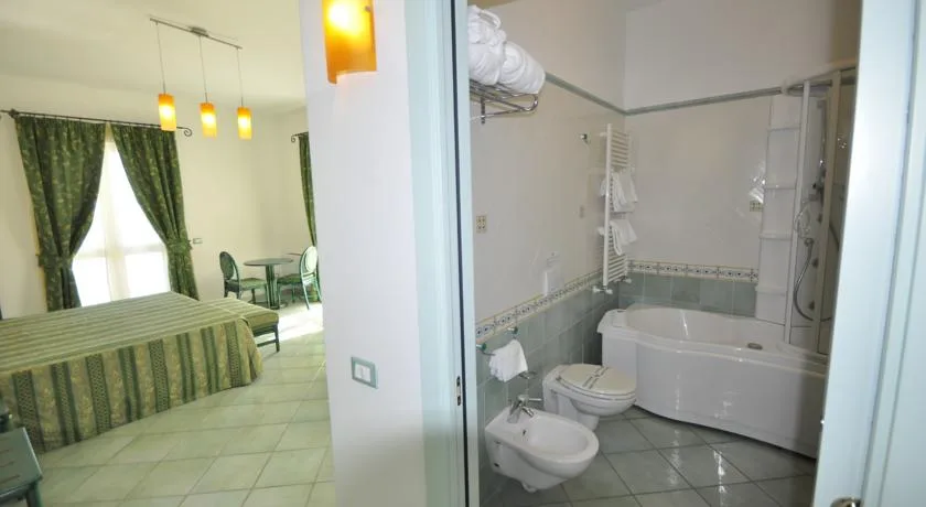Bagno con vasca e vista sulla camera con tessuti verdi