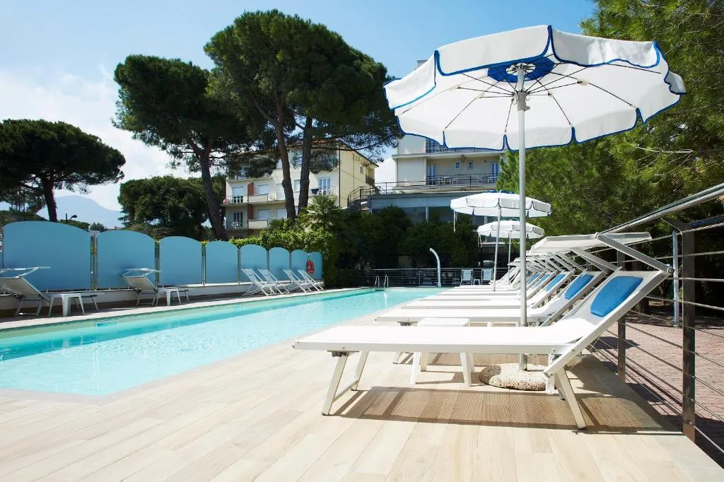 Bordo piscina con lettini, ombrelloni e vegetazione circostante