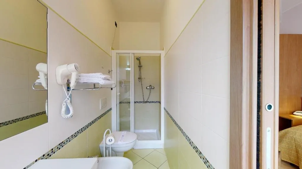Bagno stretto con doccia, bidet, asciugacapelli e piastrelle verdi