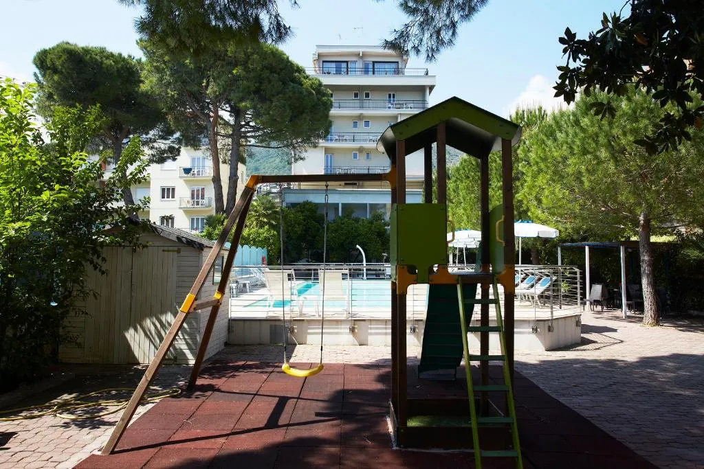 Area giochi per bambini con altalena e scivolo vicino alla piscina