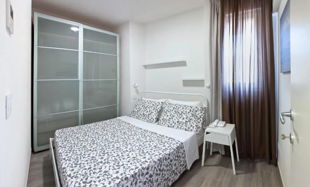Camera moderna con letto matrimoniale, armadio in vetro e comodino bianco