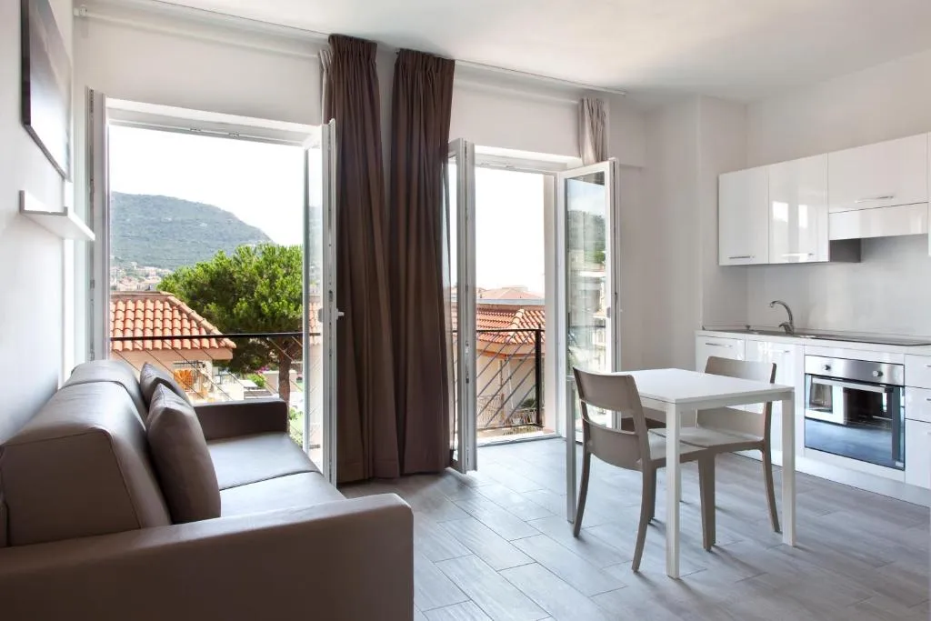 Soggiorno con cucina, divano in pelle e balcone con vista sulle montagne