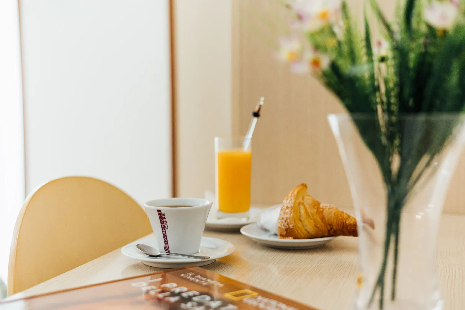 Colazione servita con caffè, succo d'arancia e croissant su tavolo con fiori