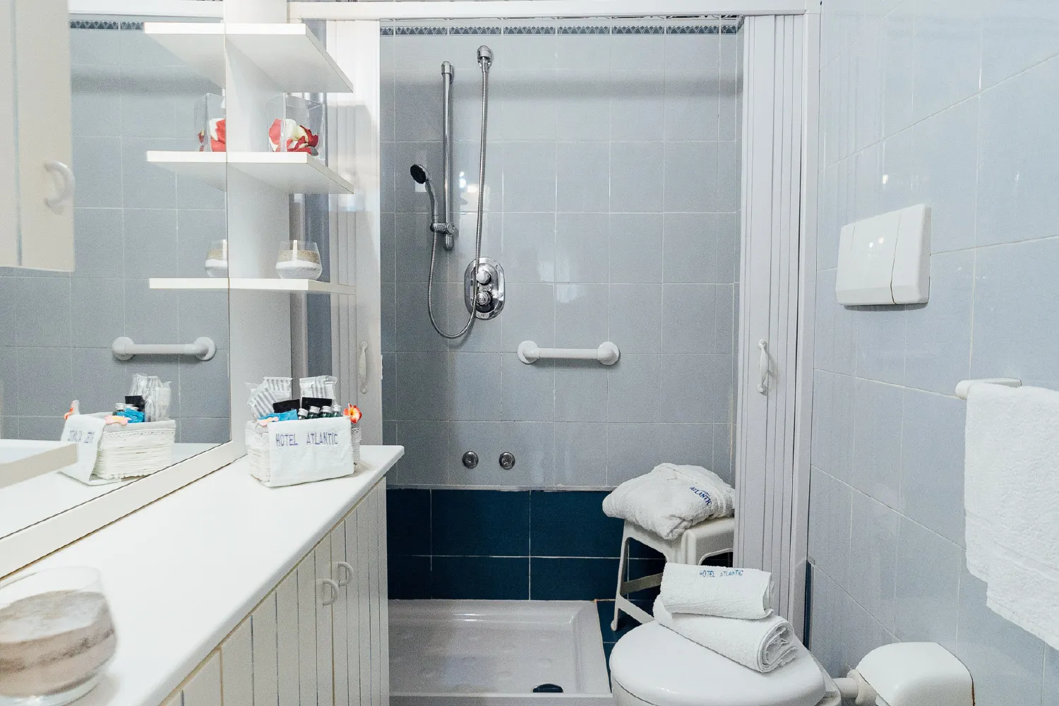Bagno con doccia, sgabello, mensole e set di cortesia Hotel Atlantic
