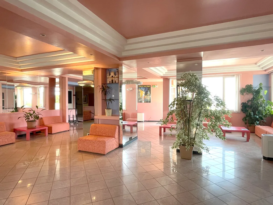Hall dell'hotel con divani arancioni, piante e pavimento lucido