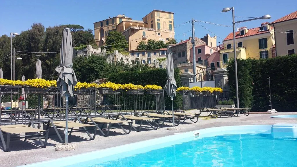 Bordo piscina con lettini e ombrelloni chiusi, vista sugli edifici storici della collina