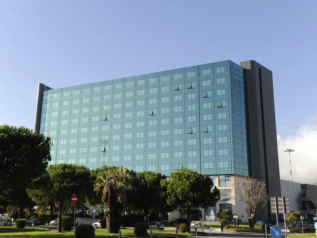 Facciata moderna in vetro dell'hotel con alberi e palme in primo piano