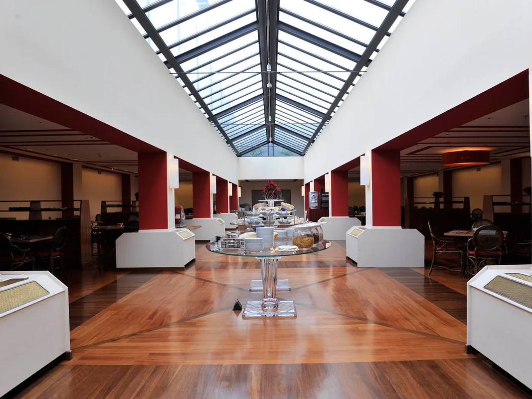 Sala ristorante per la colazione con buffet centrale, soffitto vetrato e pavimento in legno