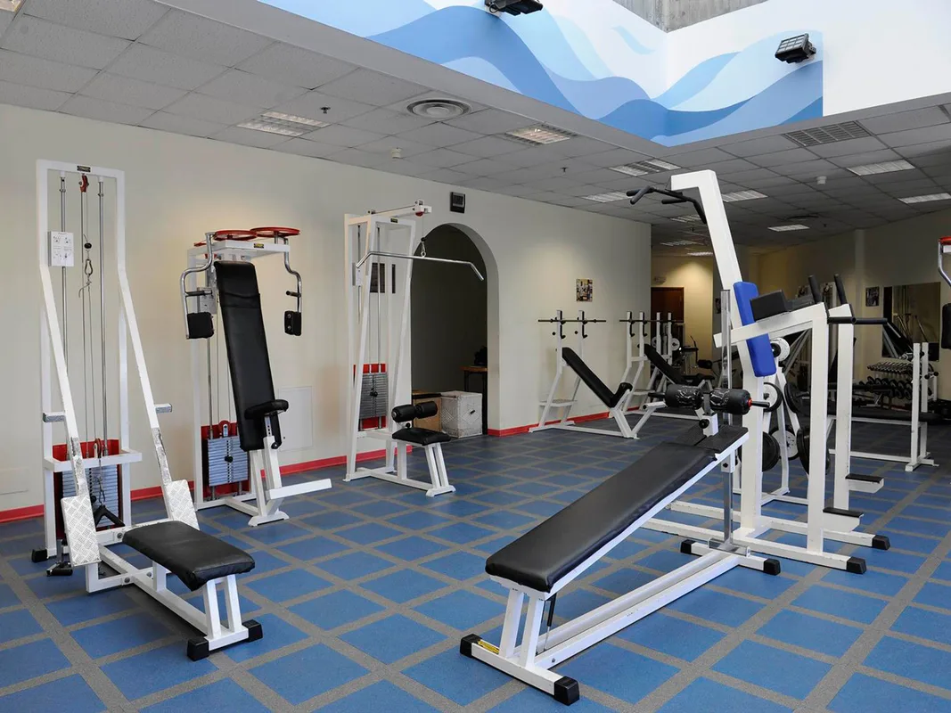 Sala fitness con attrezzi per pesi e panche su pavimento azzurro