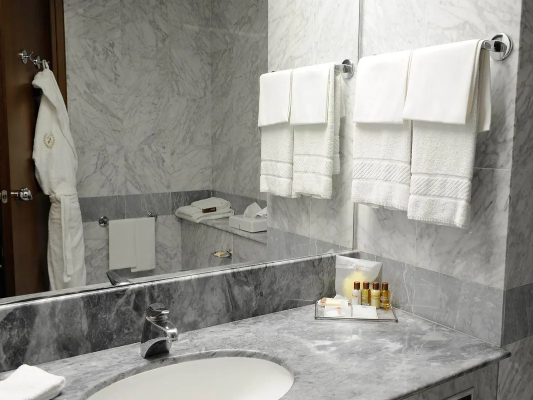 Dettaglio del bagno in marmo grigio con lavabo, asciugamani, accappatoio e set di cortesia