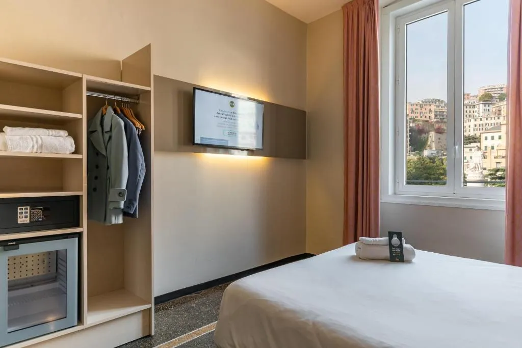 Camera con letto matrimoniale, armadio aperto, TV e finestra con vista sulla città