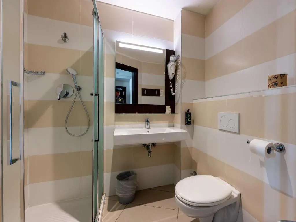 Bagno della camera con doccia, lavabo, specchio e pareti a righe beige