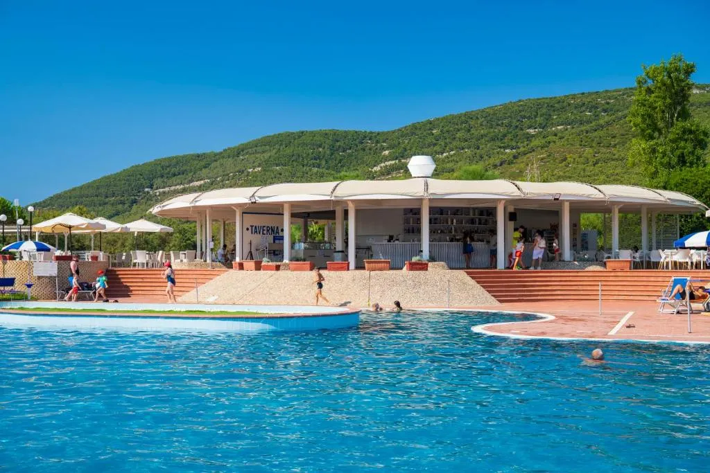 Bar Taverna a bordo piscina con persone in acqua e colline verdi