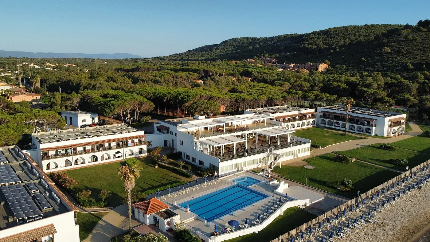 Vista aerea degli edifici del resort con piscina e collina boscosa sullo sfondo