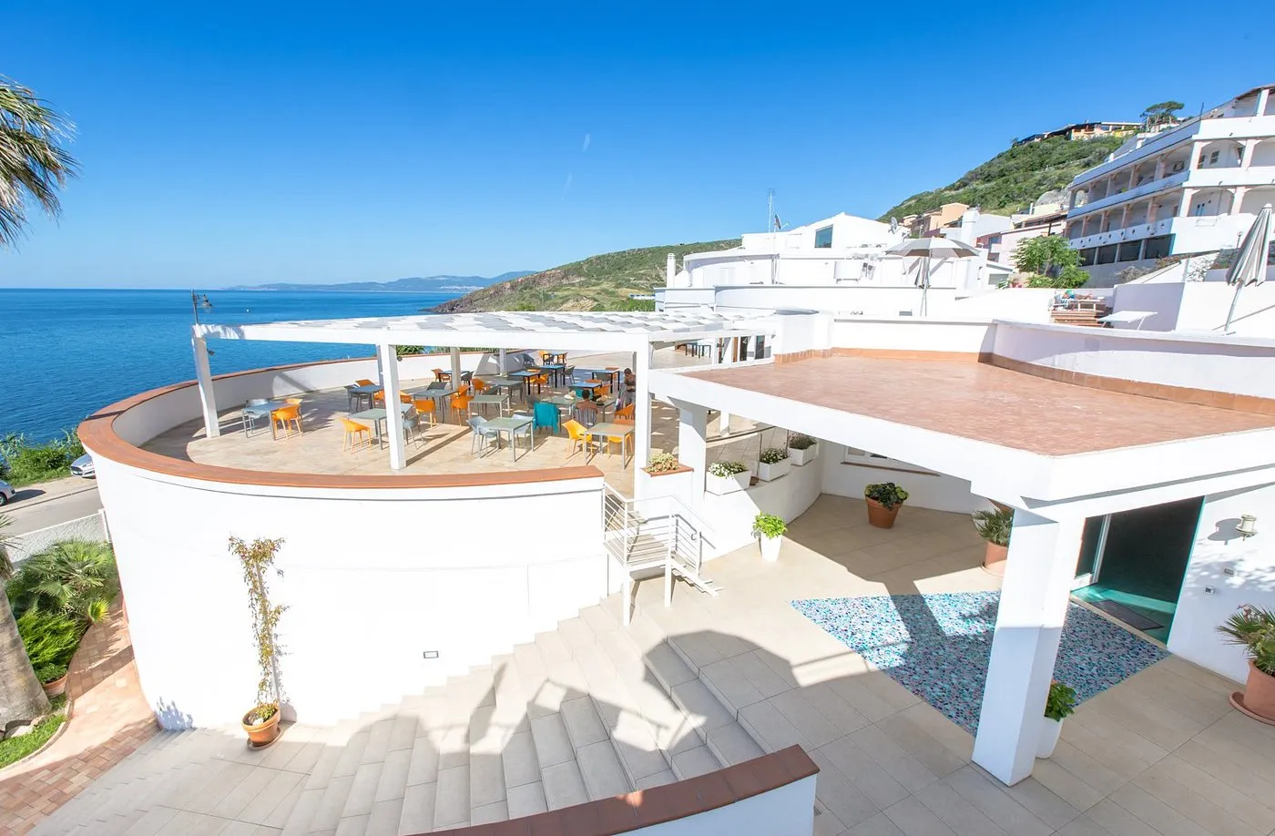 Terrazza esterna con tavoli colorati e pergolato affacciata sul mare