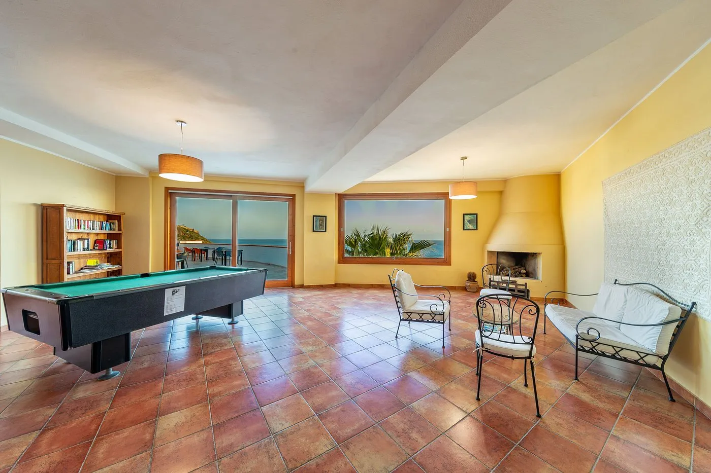 Sala comune con tavolo da biliardo, camino e vista mare