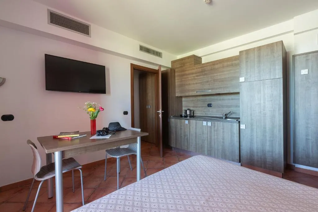 Monolocale con angolo cottura in legno, tavolo da pranzo e TV a parete