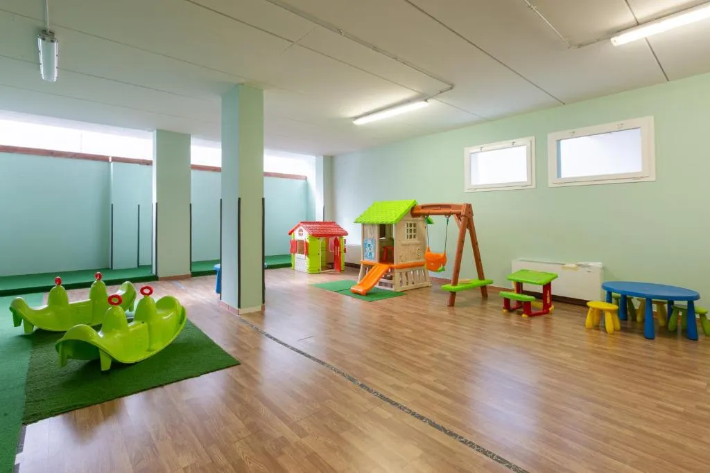Sala giochi per bambini con casette, scivolo, altalena e giochi colorati