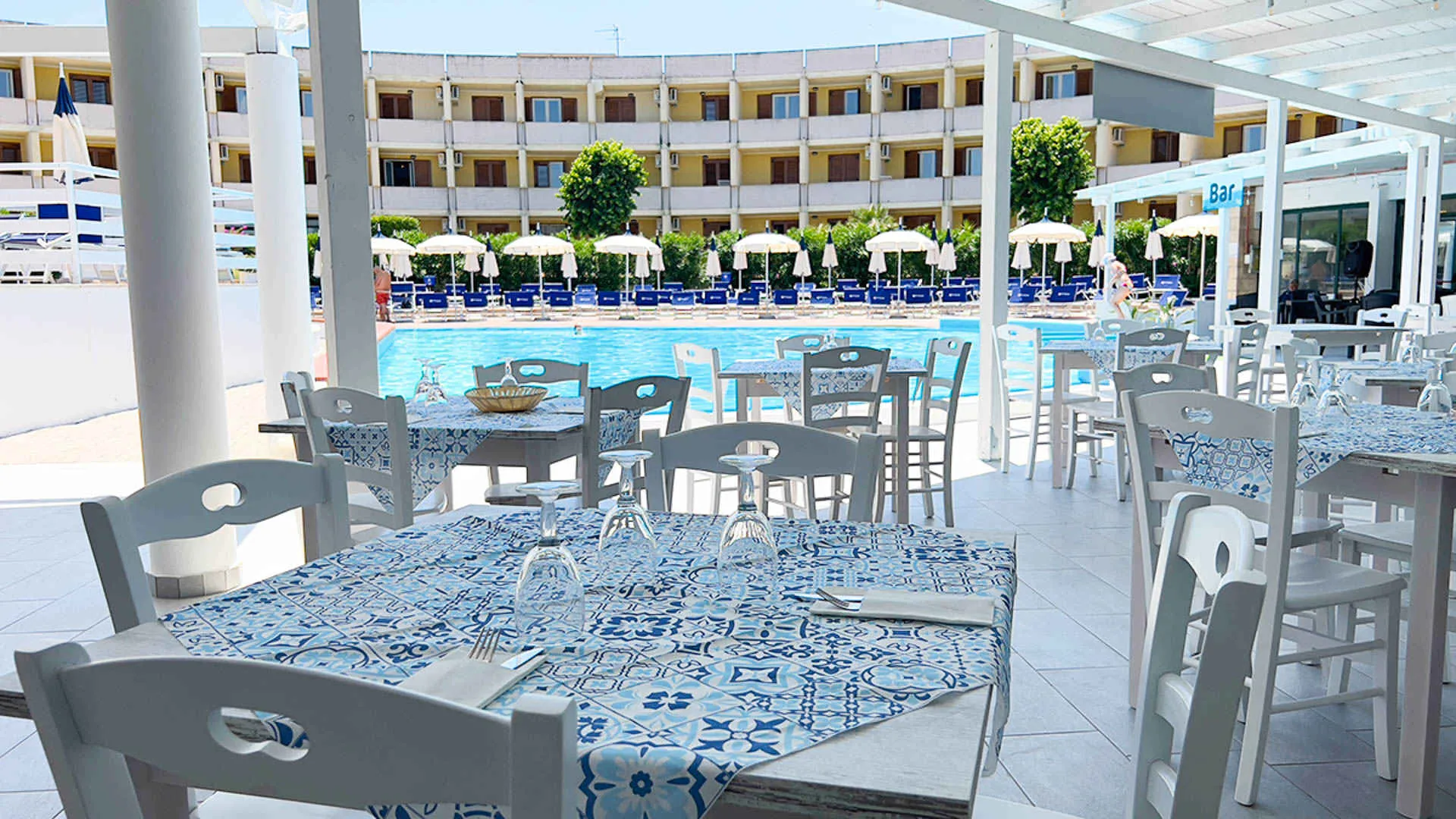 Ristorante all'aperto con tavoli e tovaglie a fantasia blu vicino alla piscina