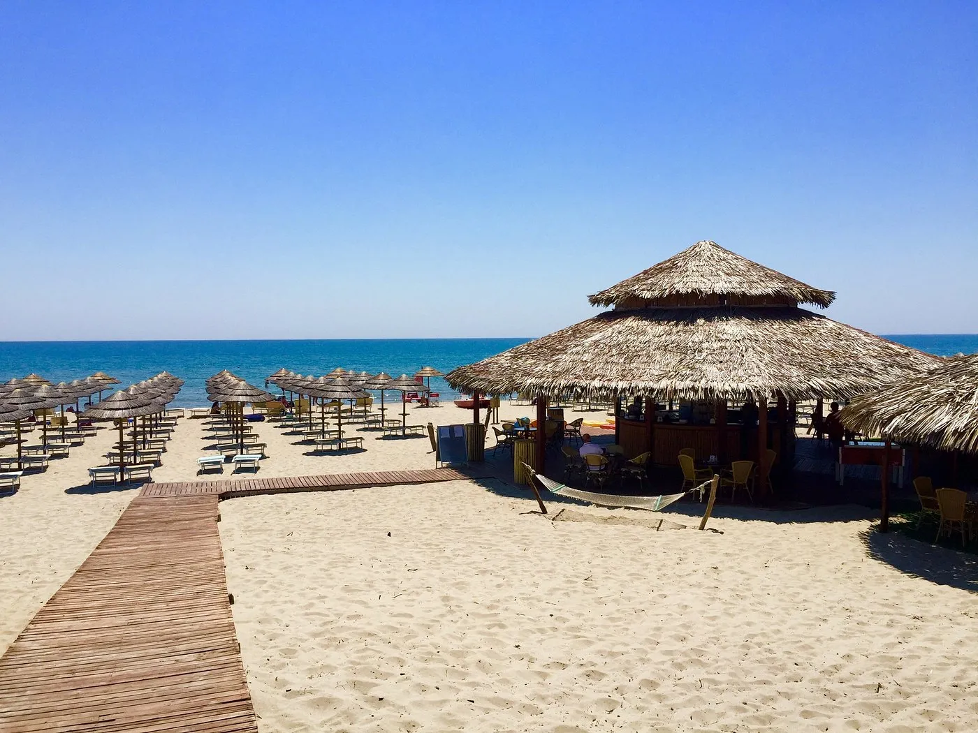 Spiaggia sabbiosa con ombrelloni in paglia e capanna bar vista mare