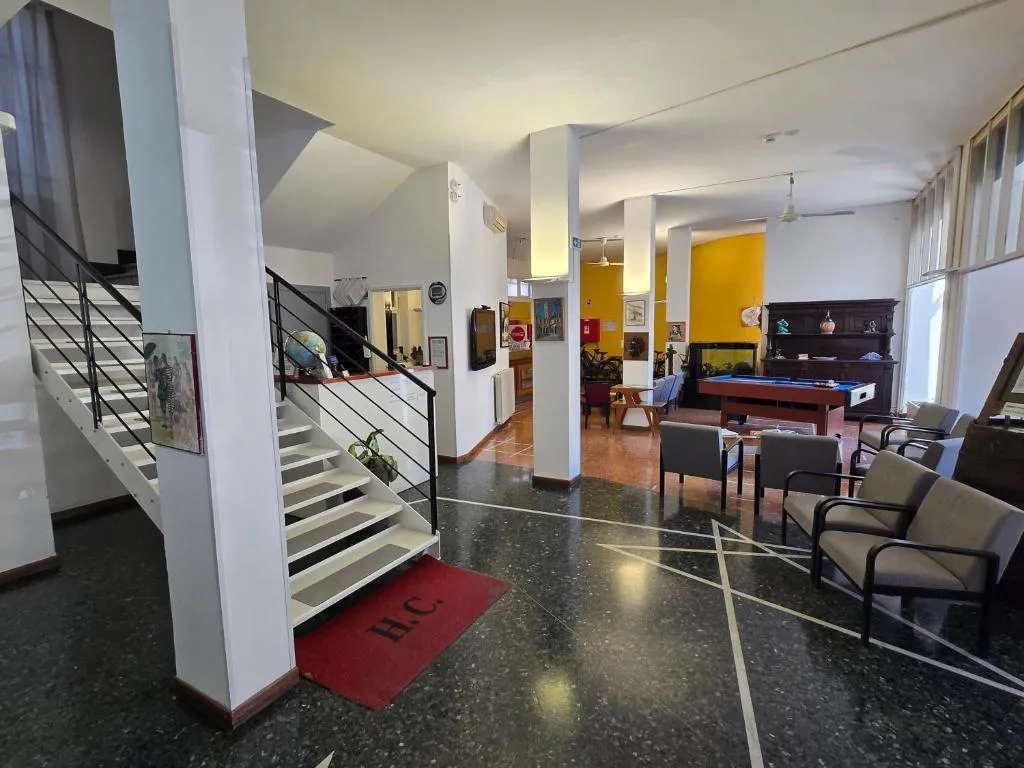 Ampia hall con scala bianca, zona soggiorno e area con tavolo da biliardo