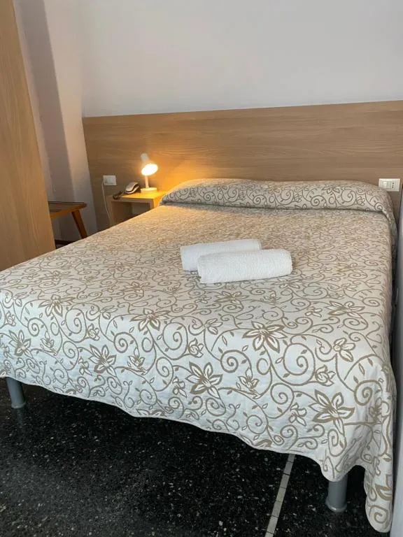 Letto matrimoniale con copriletto floreale e asciugamani piegati