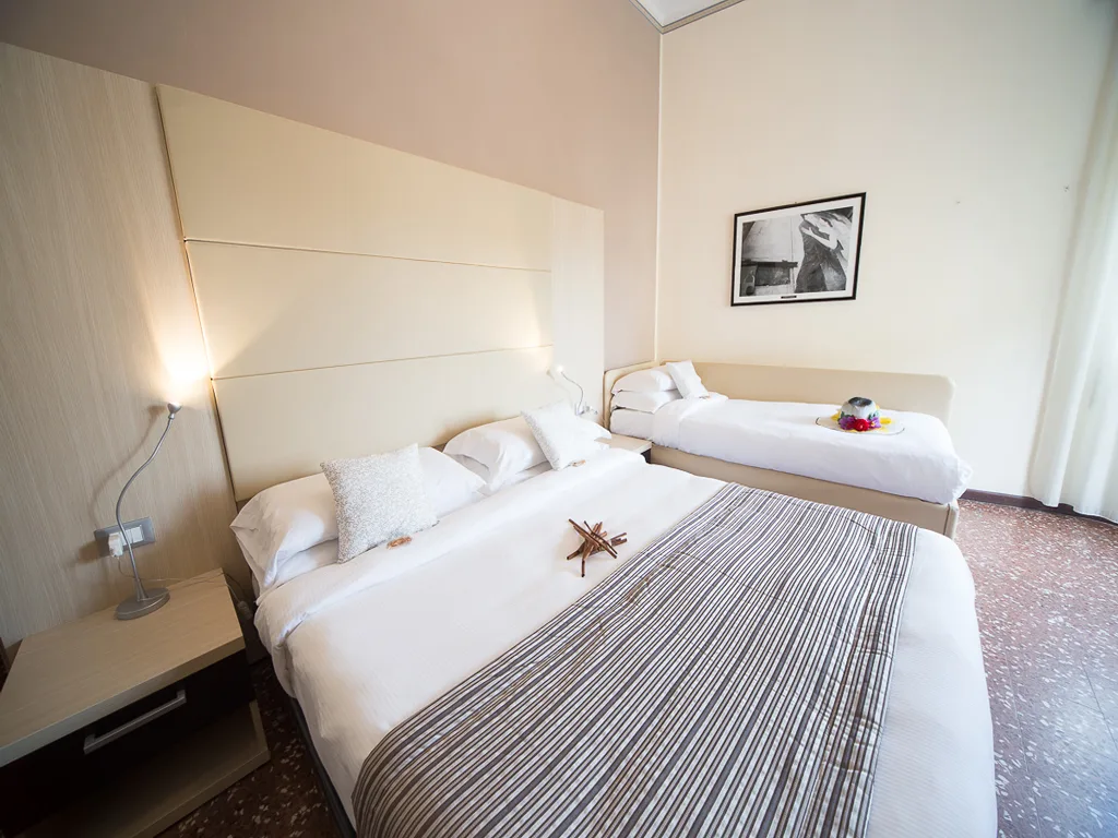 Camera tripla con letto matrimoniale e letto singolo, arredamento moderno in tonalità neutre