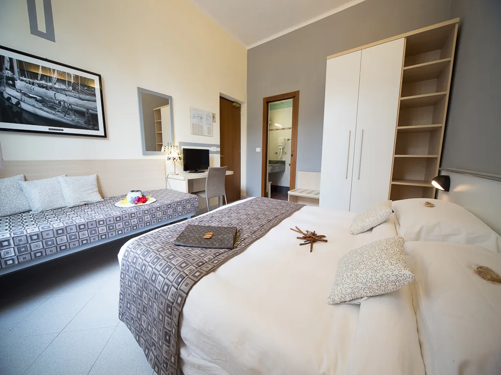 Camera tripla spaziosa con letto matrimoniale, divano letto e armadio bianco