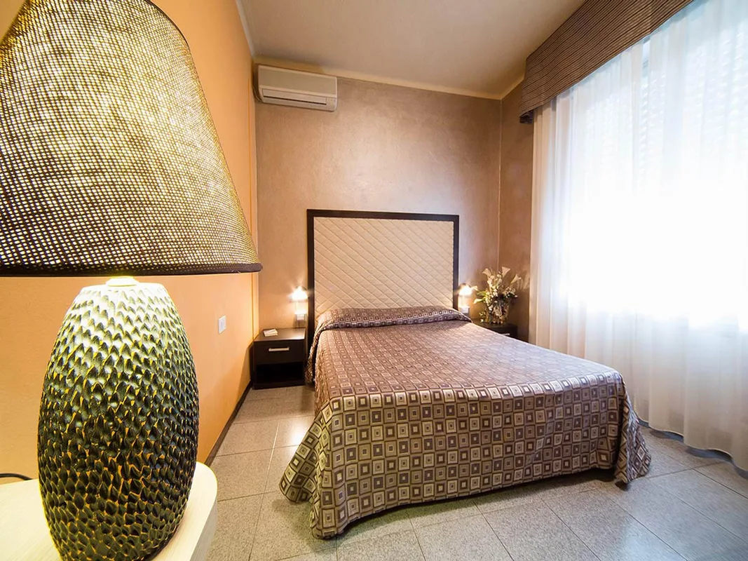 Camera singola con letto, grande lampada decorativa e finestra luminosa