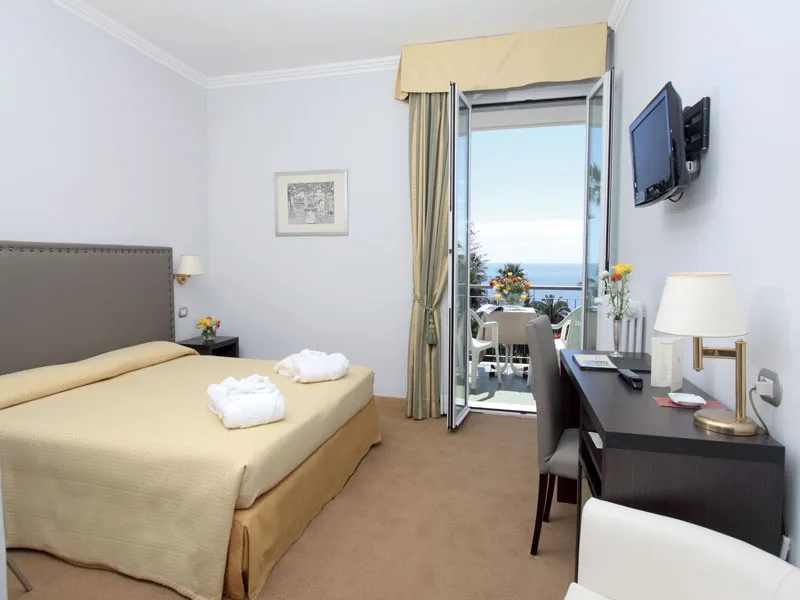Camera con letto matrimoniale, scrivania, TV e balcone con vista mare
