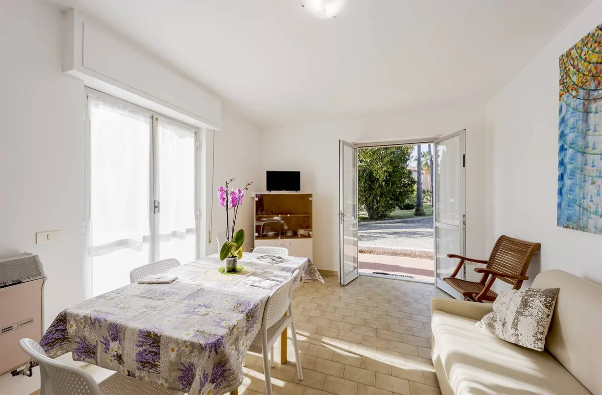 Soggiorno luminoso con tavolo da pranzo, divano e porta finestra aperta sul giardino