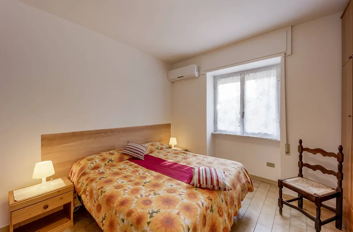 Camera da letto matrimoniale con copriletto floreale, comodino e aria condizionata