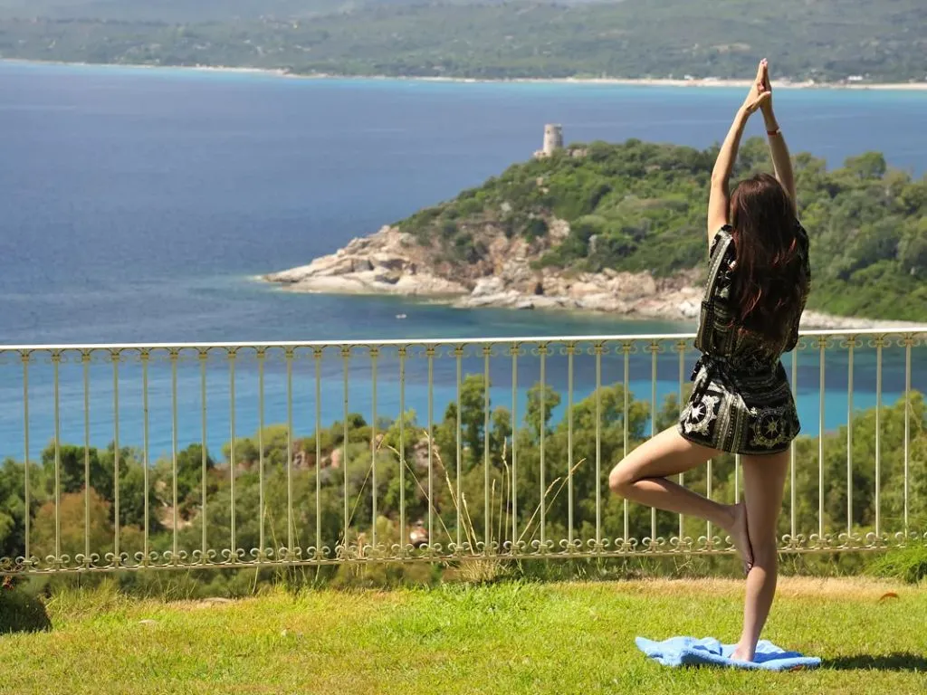 Donna pratica yoga su un prato con vista panoramica sul mare e la costa