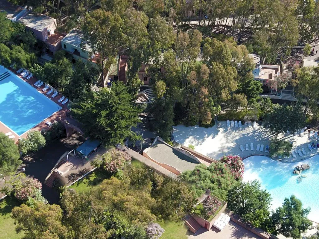 Vista aerea di due piscine immerse nel verde con lettini e vegetazione rigogliosa