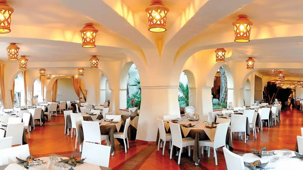 Sala ristorante in stile mediterraneo con archi, lanterne e tavoli apparecchiati
