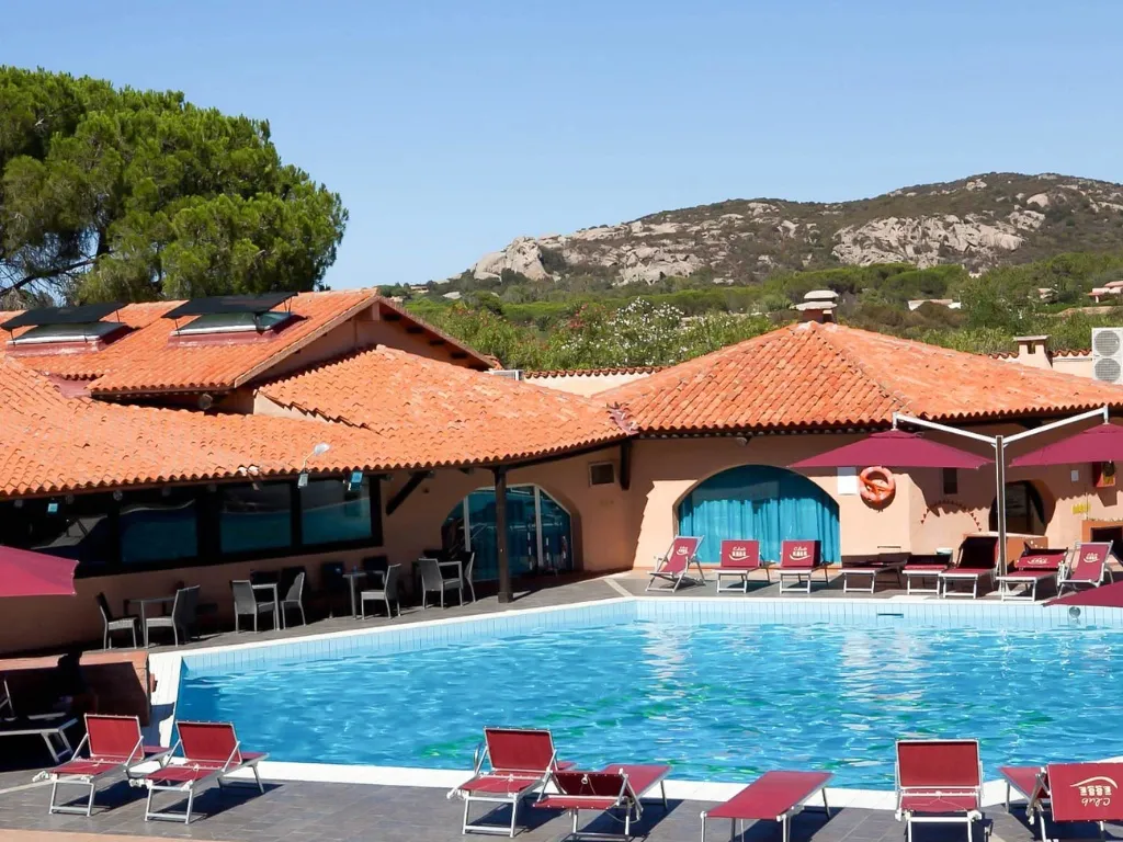 Piscina del resort con lettini rossi e vista sulle colline