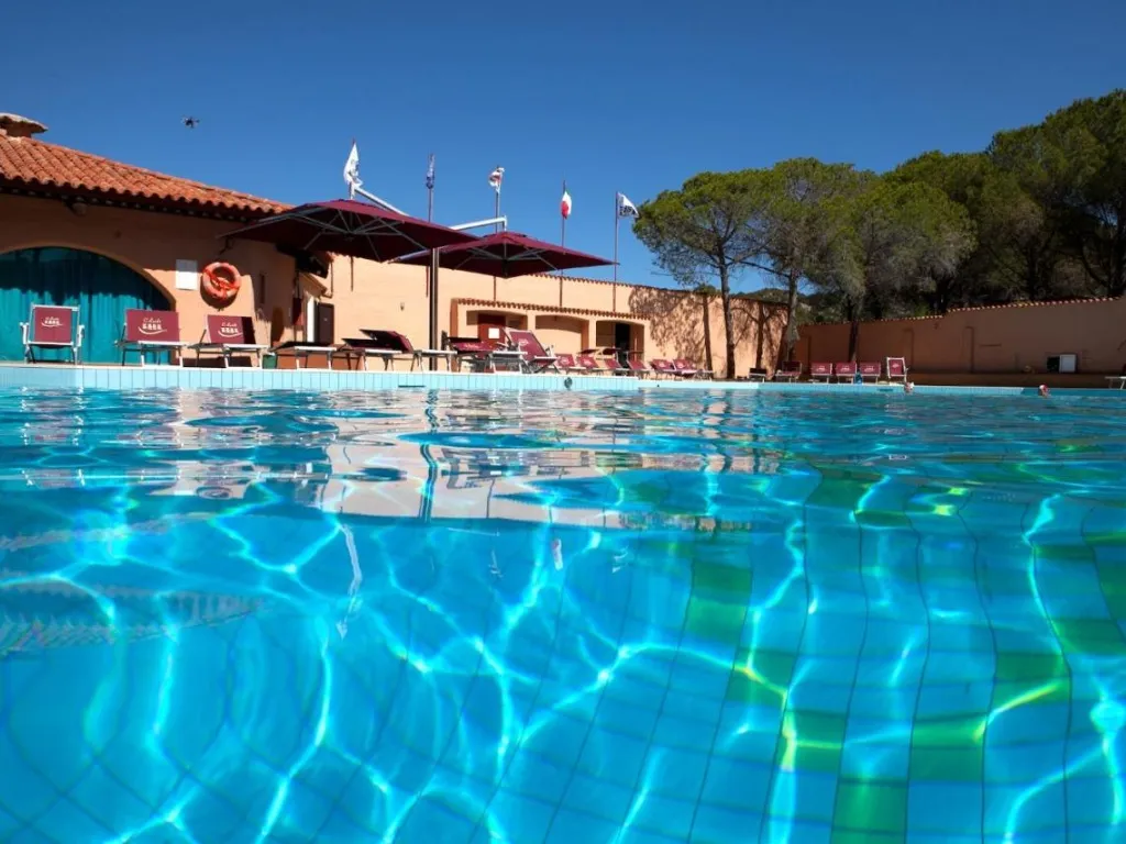 Piscina azzurra con edificio del resort e bandiere sullo sfondo