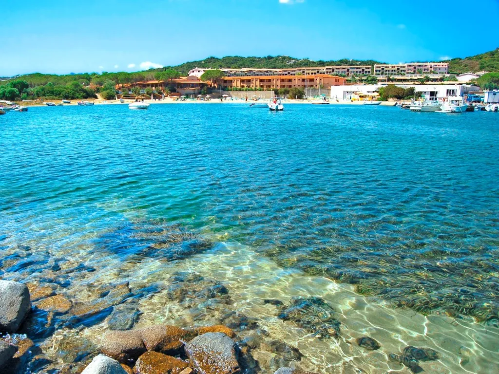Spiaggia con acqua cristallina, barche ormeggiate e resort sullo sfondo