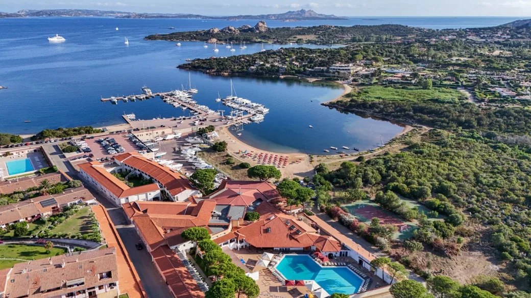 Vista aerea del resort con piscina, spiaggia e porto turistico in Sardegna