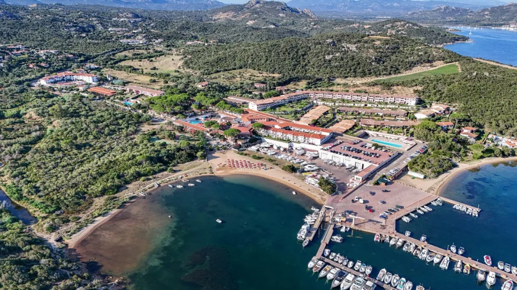 Veduta aerea del complesso turistico con porto, spiaggia e colline