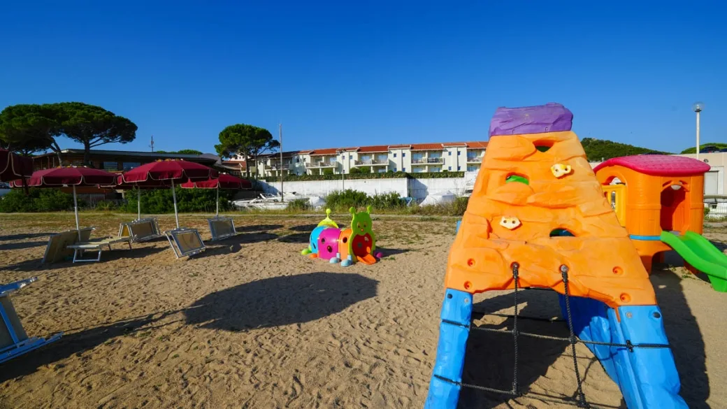 Area giochi per bambini in spiaggia con scivolo colorato e ombrelloni
